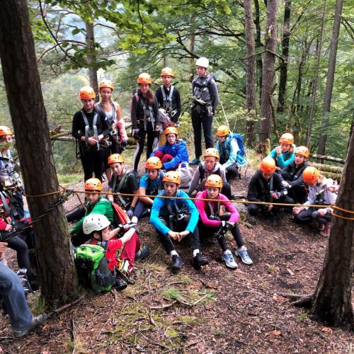 Schüler:innen im Hochseilklettergarten am Waldboden sitzend