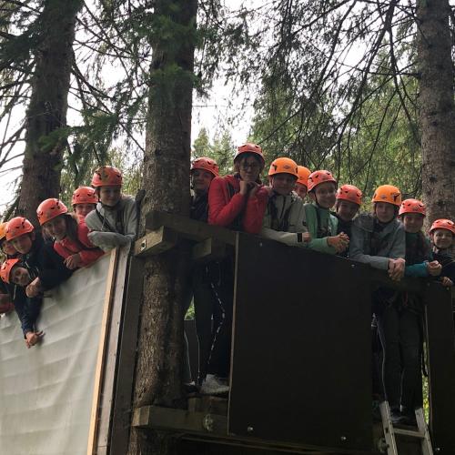Schüler:innen in einer Gruppe im Hochseilklettergarten auf einem Boden stehend