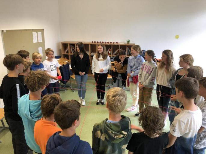 Schüler*innen in einem Kreis in einer Klasse stehend