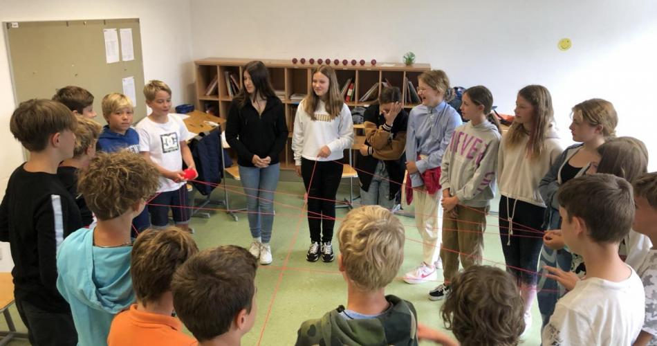 Schüler*innen in einem Kreis in einer Klasse stehend