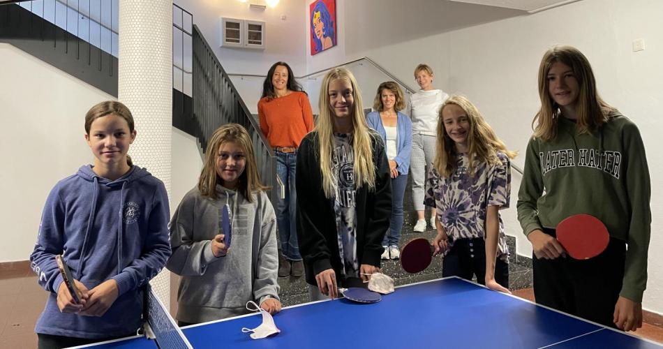 Schüler:innen mit Schlägern und Bällen bei einem Tischtennistisch 